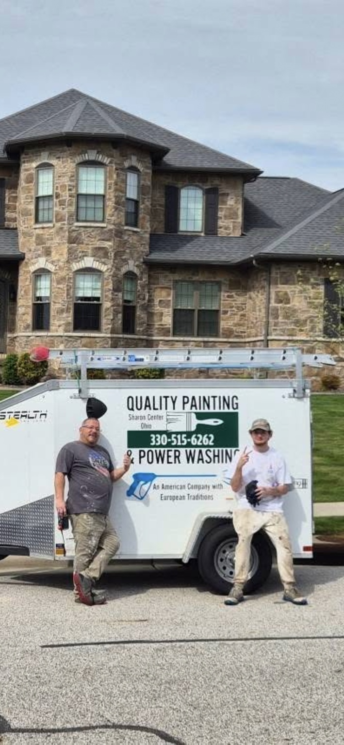 Adam and a team member standing in front of the Quality Painting work trailer